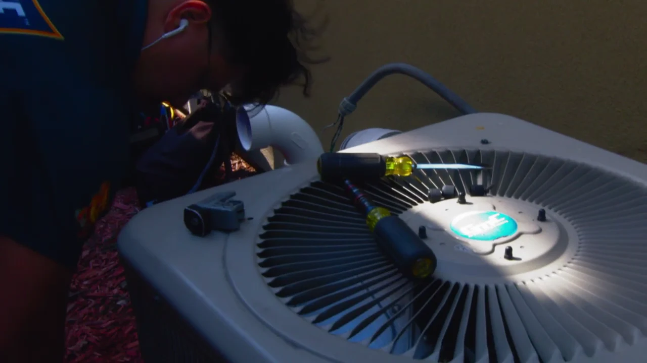 A Warm Welcome technician servicing a residential air-conditioning unit.